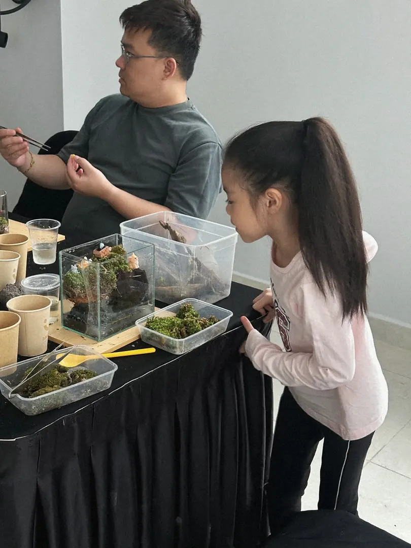 A parent and child building a terrarium together