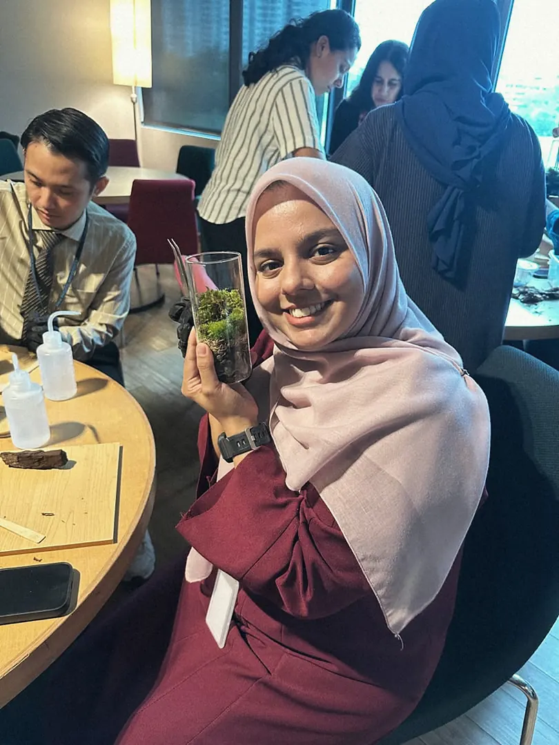 A guest at a workshop holding up the terrarium she made